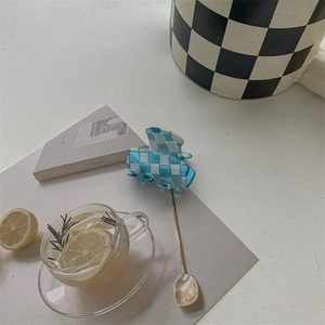 Close-up of blue and white checkered mini hair claw clip with mirror finish on flat lay
