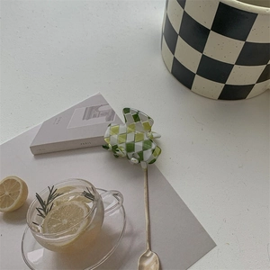 Detail view of green and white checkerboard hair claw clip among lifestyle decorations