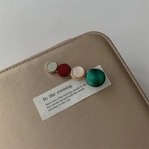 Detail view of four-color circular pearl hair clips on a premium brown leather background