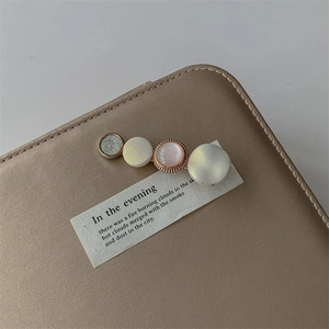 Close-up of pearl hair clip with glitter and pastel discs on premium leather surface