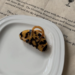 Détail macro d'une mini pince à cheveux léopard sur une assiette en céramique