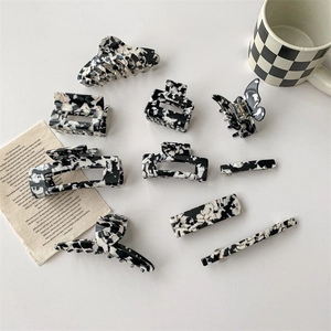 Ensemble élégant de pinces à cheveux motif vache et barrettes en acétate sur fond blanc