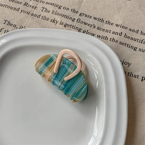 Détail d'une pince à cheveux demi-cercle avec texture marbrée sur une assiette blanche