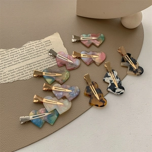 Set of heart-shaped acetate hair clips with marble patterns on a vintage leather mat