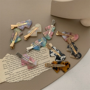 Colorful heart-shaped acetate hair clips with marble texture on vintage paper background
