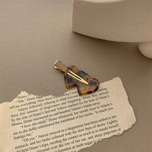 Macro detail of tortoiseshell heart shaped acetate hair clip with gold metal duckbill grip