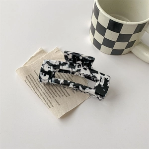 Détail d'une grande pince à cheveux rectangulaire en acétate avec motif de vache bicolore