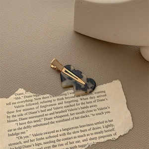 Detail of marble pattern acetate hair clip with golden metal duckbill clamp design