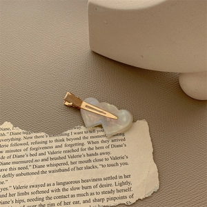 Detail of elegant gold double heart hair clips with pearl finish on vintage paper