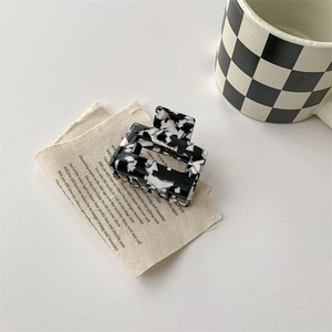 Gros plan d'une pince à cheveux rectangulaire à motif vache noir et blanc sur un bureau