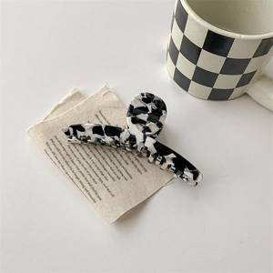 Détail d'une pince à cheveux motif vache marbré avec design croisé sur fond de tissu