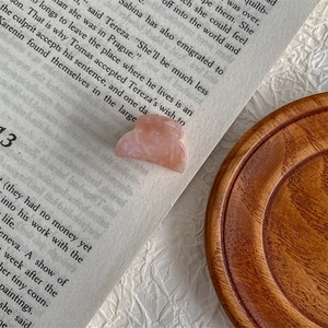 Macro detail of a small pink marble textured hair claw clip on a vintage book page