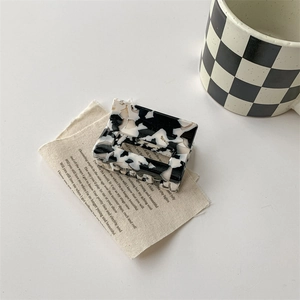 Détail d'une pince à cheveux rectangulaire avec motif marbre noir et blanc sur lin