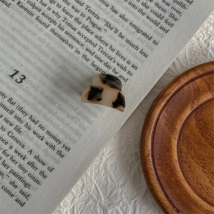 Macro view of a mini tortoiseshell acetate hair claw clip on an open vintage book