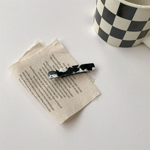 Vue détaillée de la pince à cheveux avec motif vache noir et blanc et texture marbre