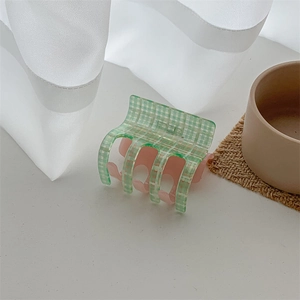 Detailed view of the green checkered pattern and pink teeth of the acetate hair claw clip