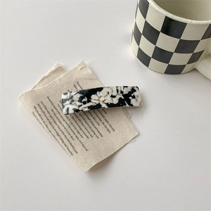 Détail d'une pince à cheveux motif vache sur un tissu vintage avec une esthétique rétro