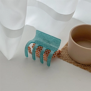 Close-up of a pink and green checkered hair claw clip with a glittery acetate finish