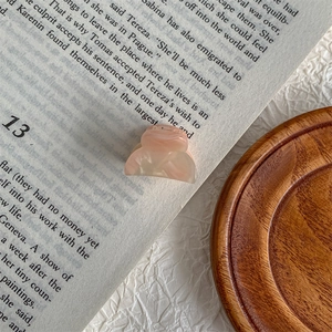 Detailed close-up of a mini light pink marble acetate hair claw on a wooden tray