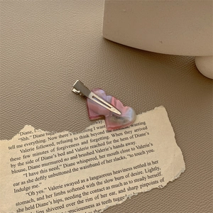 Detail shot of heart-shaped pink resin hair clip on vintage paper with metal clip back