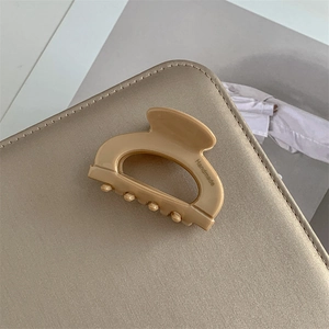 Dettaglio della pinza per capelli in acetato beige con incisione handmade su superficie