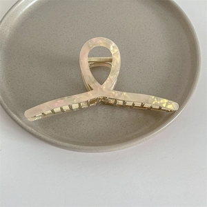 Detalle de la pinza para el pelo de acetato crema jaspeado con muelle de metal dorado de lujo