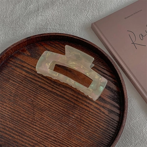 Close-up of marble acetate hair claw clip with iridescent finish on wooden tray