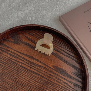 Detail of French vintage hair claw with iridescent pearl finish on dark wood tray