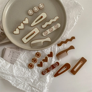 Retro cream and brown hair clips set with heart and smiley face designs in a ceramic tray