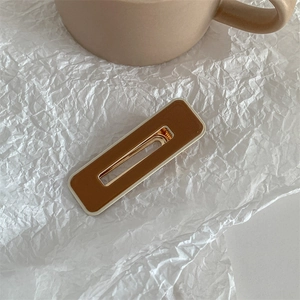 Close-up of a brown and cream acrylic hair clip on white textured paper background