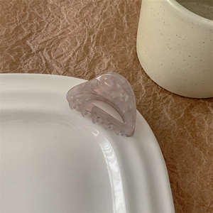 Détail de la pince à cheveux marbrée lavande sur le bord d'une assiette blanche
