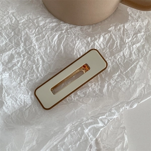 Detail of cream white duckbill hair clip with brown edges and gold metal spring clip