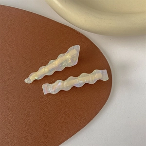 Close-up of wavy pearlescent hair clips set on leather with elegant French aesthetic