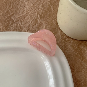 Détail macro d'une pince à cheveux en acétate marbré rose avec texture élégante