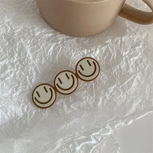 Detail of three cute cream smiley face hair clips with a smooth alloy finish in ins-style