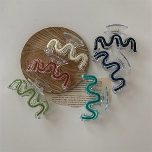 Set of wavy acrylic hair claws in six colors displayed on a wooden tray with minimalist styling
