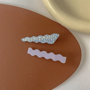 Detail view of retro oil painting style duckbill hair clips with wave and pearl texture