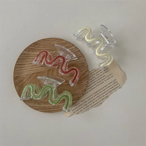 Acrylic wave pattern hair claw clips in red green and yellow displayed on wooden tray