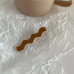 Macro shot of wave-shaped brown and cream hair clip on artistic paper background
