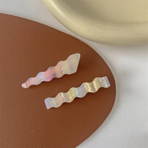 Close-up of wavy hair clips with iridescent oil painting texture on leather surface