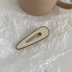 Detail of cream drop hair clip with brown trim on wrinkled paper background