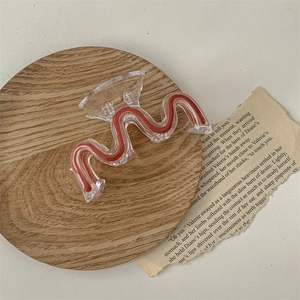 Detailed close-up of a large wave-shaped acrylic hair claw with wood-grain texture inlay