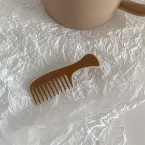 Detail view of a comb-shaped hair clip in dark coffee and cream white colors