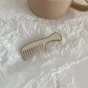 Detailed close-up of a cream and brown comb-shaped hair clip on a soft textured background