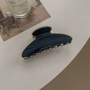 Détail de la pince à cheveux bicolore marine et crème avec une finition brillante
