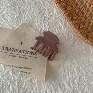 Close-up of brown acetate hair claw clip with handmade lettering on a neutral background