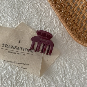 Detail of wine red acetate hair claw clip with handmade gold lettering on white fabric
