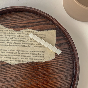 Dettaglio di un fermaglio per capelli rettangolare color crema su carta di libro vintage