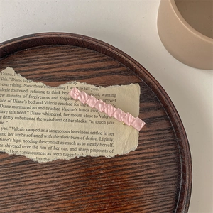 Dettaglio molletta per capelli rosa effetto marmo su carta vintage e vassoio in legno