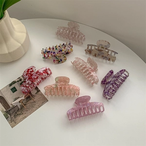 Set of 8 large marble pattern hair claw clips in various colors on a white table